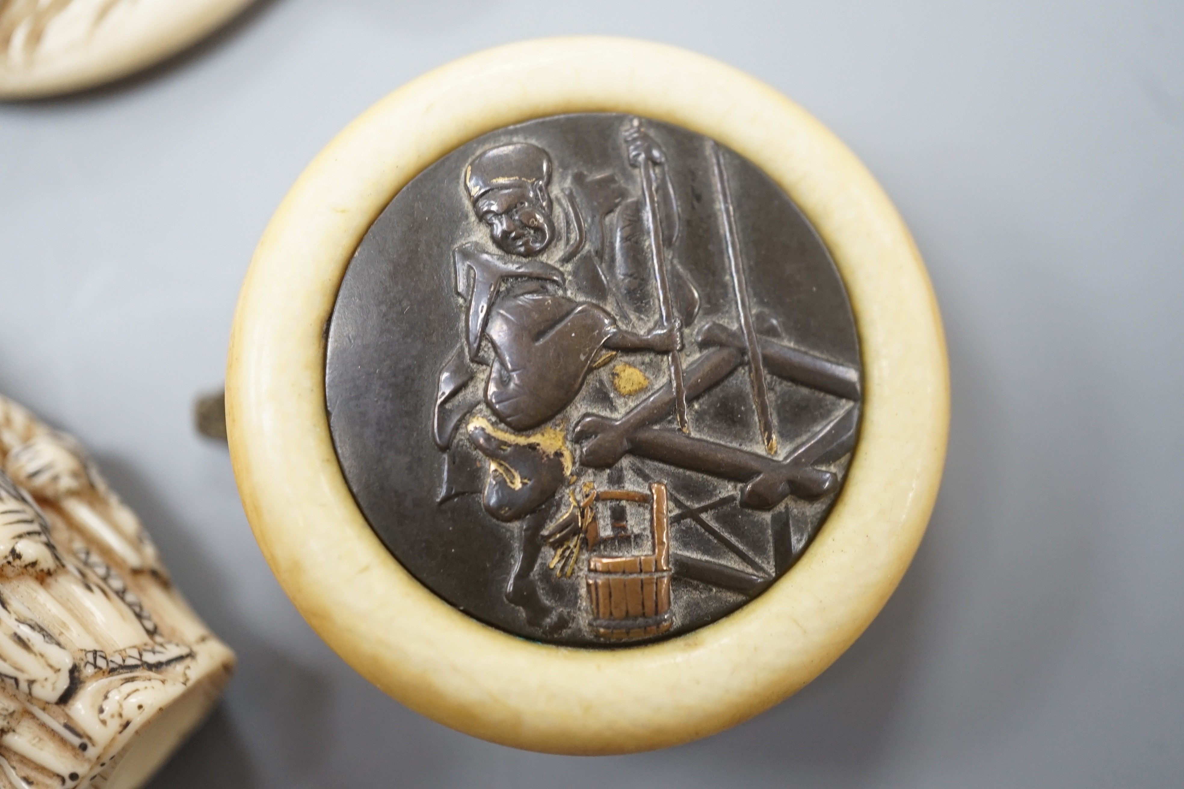 Two Japanese lacquer boxes, an ivory and bronze manju, an ivory ‘lion’ two-piece belt buckle and two simulated ivory items, late 19th/early 20th century, largest Box 11.5 cm